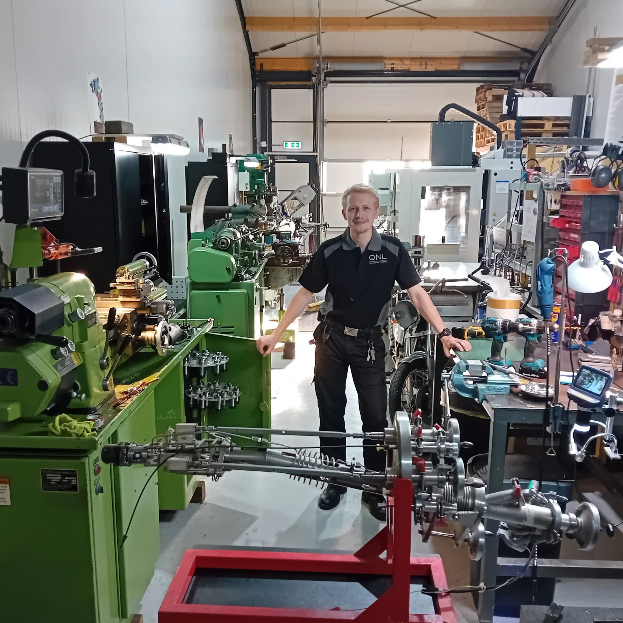 Destin Pieters, Oprichter van QNL, staat trots in de werkplaats tussen CNC- en conventionele machines, met ionenkanon in het midden – welkom in de precisie-instrumentmakerij